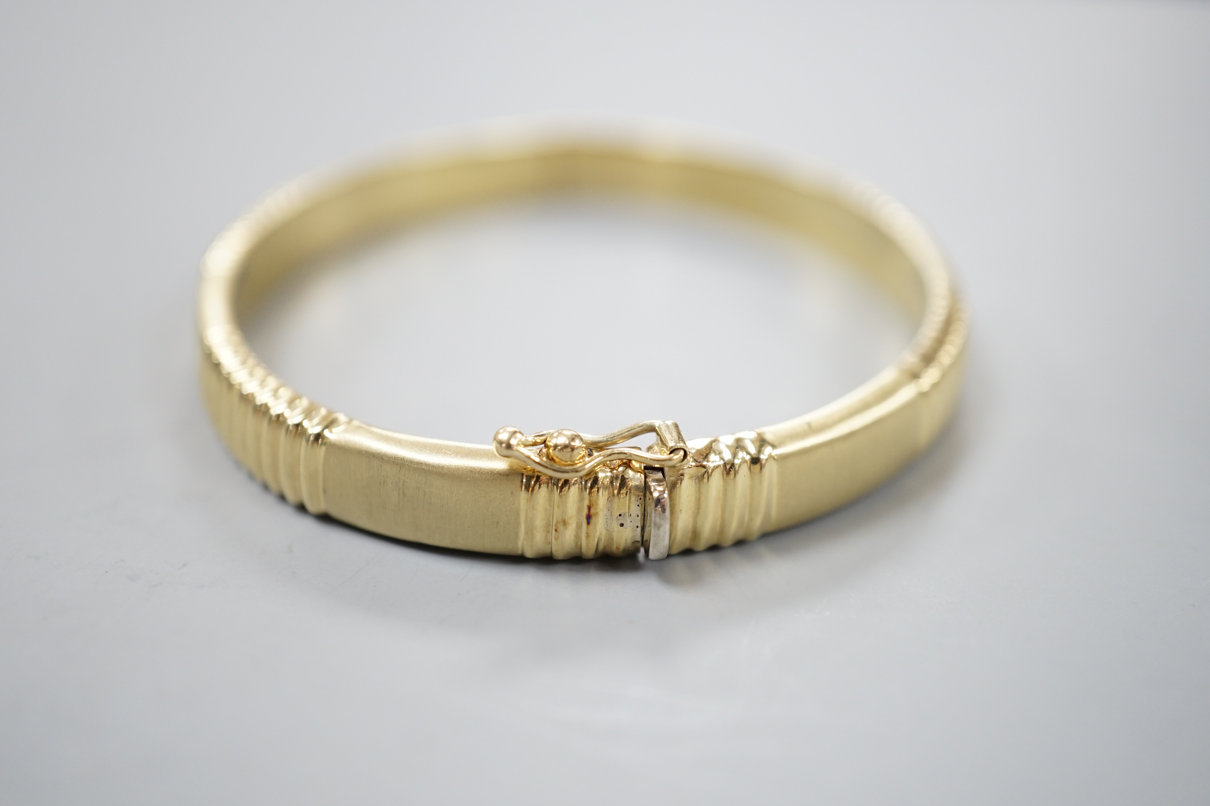 A modern 585 yellow metal hinged bangle, 12.8 grams.